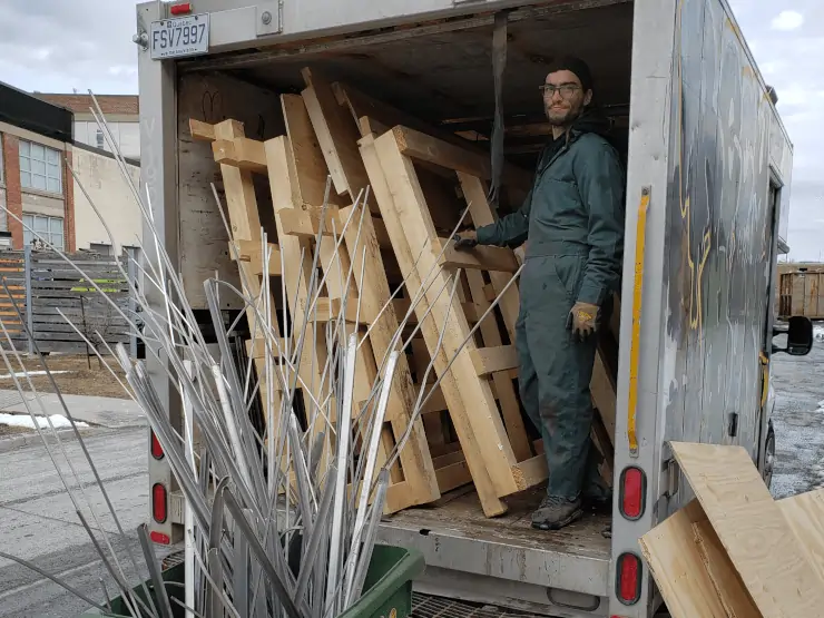 Recyborg worker standing in a truck containing wood pallets